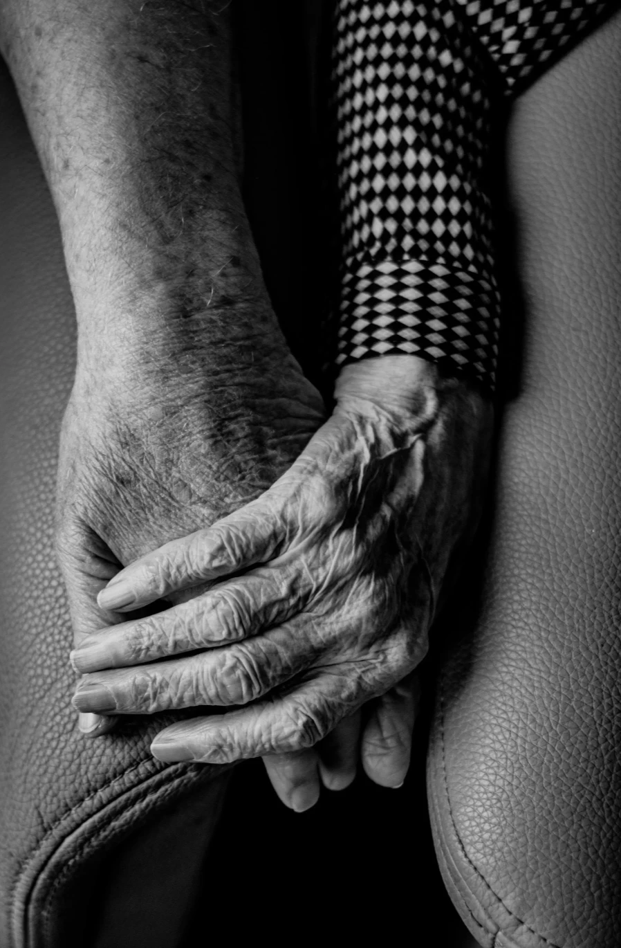 The clasped hands of an older person resting quietly