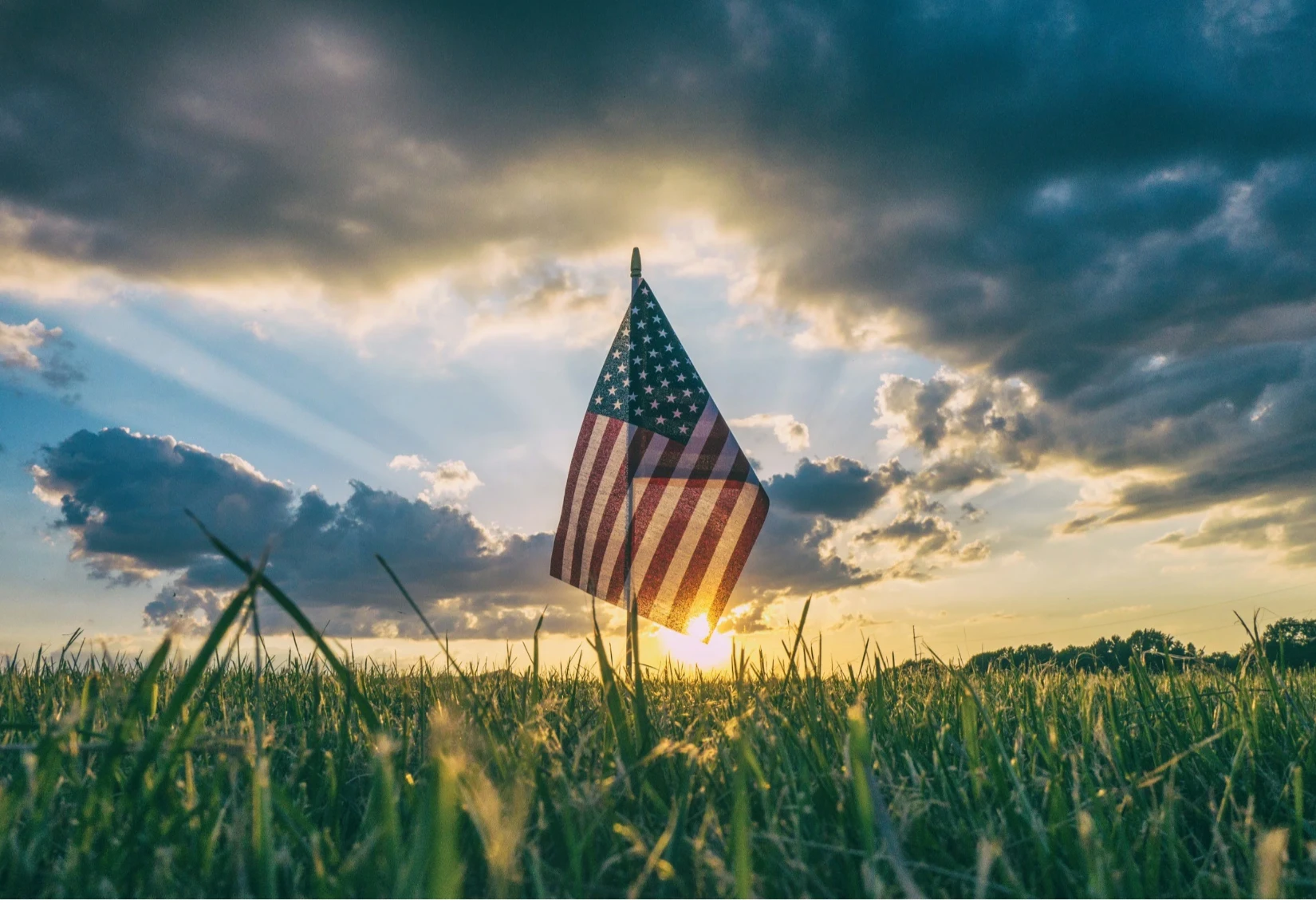 An American flag in a field at sunset